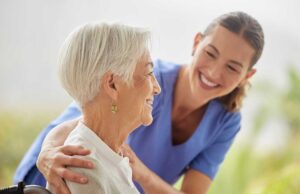 A caregiver assists a senior resident with organizing daily medications at a small table.