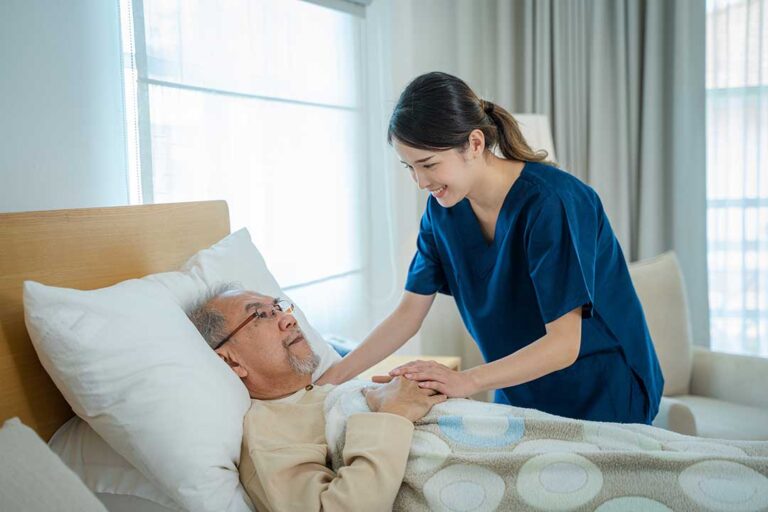 A caregiver assisting an older adult with daily activities in a comfortable residential living room.