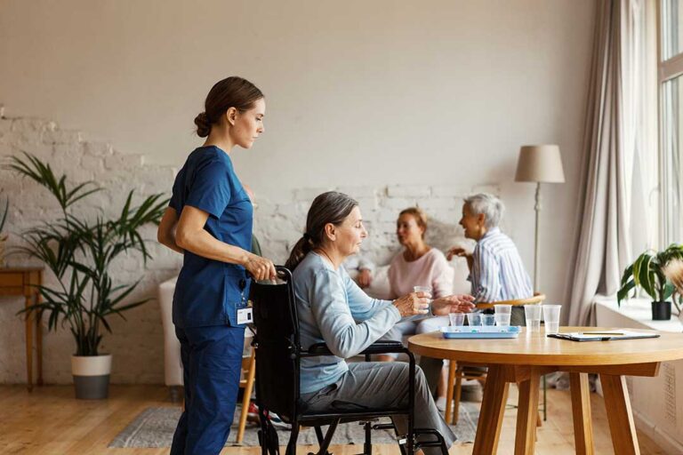 A senior resident chatting with visiting family members in a cozy, well-lit communal area.