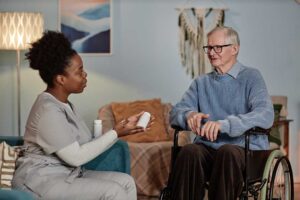 Older resident and caregiver reviewing a cultural preferences checklist beside a meal tray and prayer items.